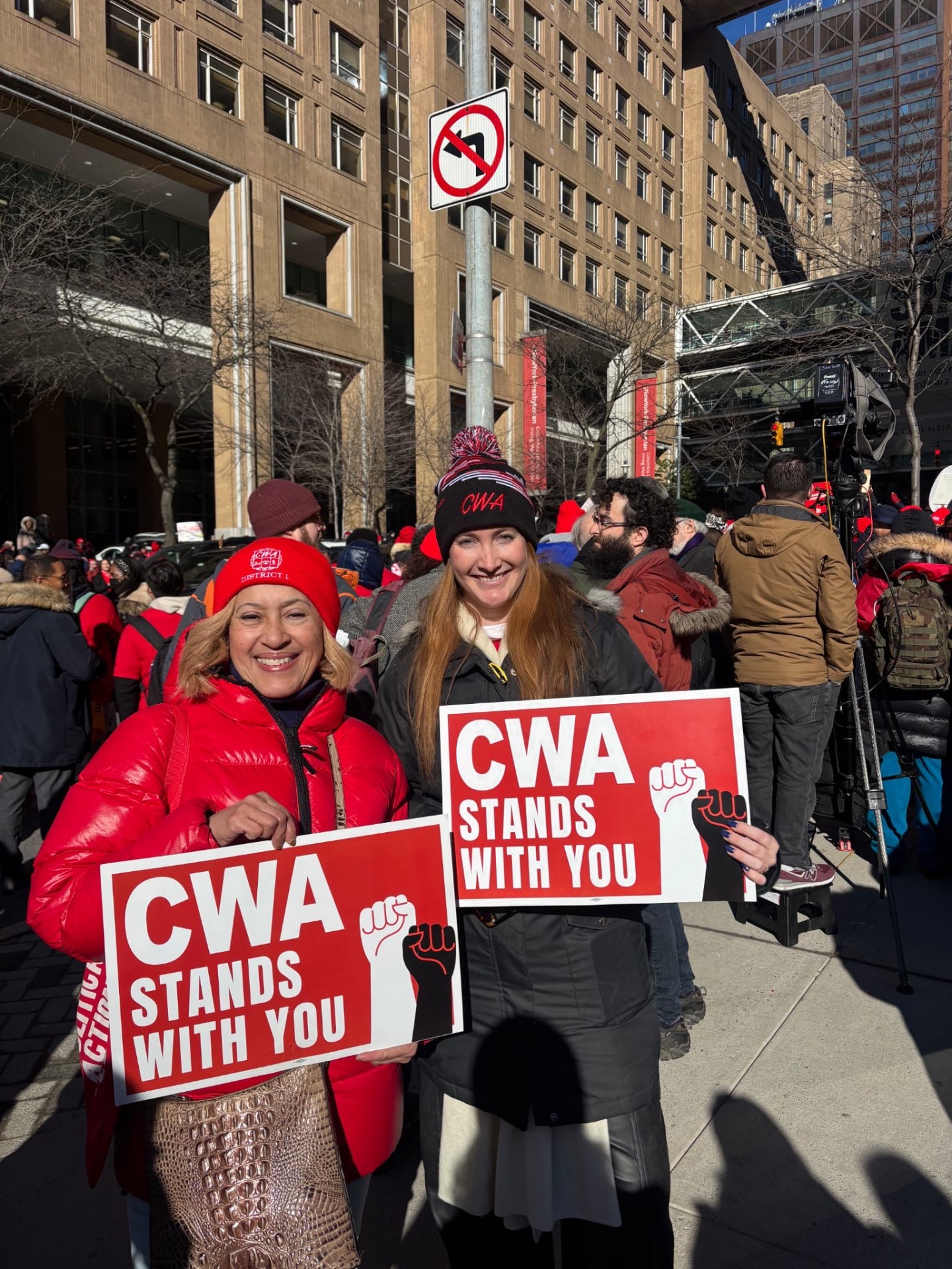 Two nurses outside a hospital holding CWA Stands With You signs.
